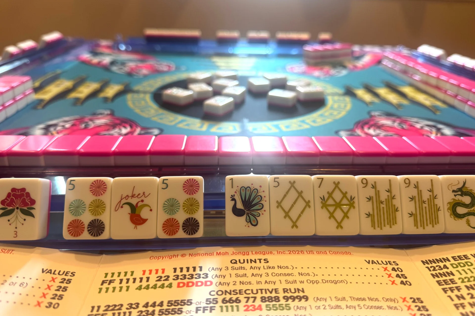 A mahjong tablescape set with tiles, racks and the National Mah Jongg League card